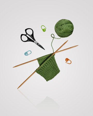 Tools for knitting warm clothes: scissors, green ball of thread, stoppers, and knitting needles with...
