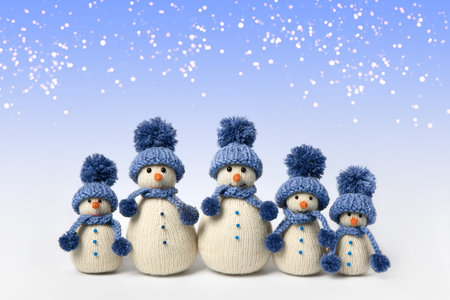 Knitted snowman in blue hat and scarf festive lights on gray background. Winter fairy tale story with your own hands, hobby. Merry Christmas and New Year greeting cardの写真素材