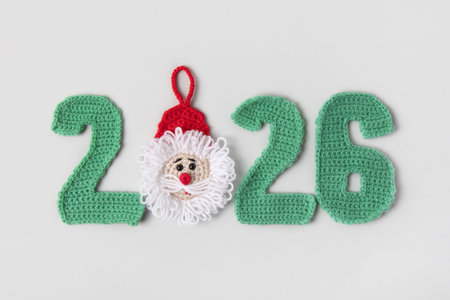 Crocheted toys Santa Claus, green Christmas tree and knitted numbers 2026 with balls of thread on...