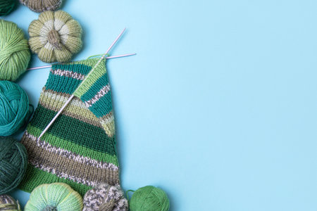 Green knitting balls with knitting needles on blue background. Set for the hobby of knitting warm clothes or toys. Concept needleworkの写真素材