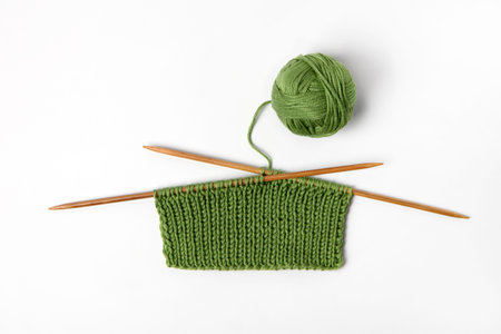 Green knitted wool on gray background with knitting needles for knitting warm clothes and hobbies...