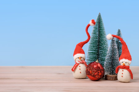 Christmas background with knitted snowmen in red hats and Christmas trees with red ball and space for text, greetings, promotions, and discounts. Christmas and New Year card.の写真素材