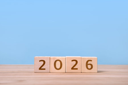 New Year 2026 postcard. Wooden cubes with numbers on a wooden table and a blue background.