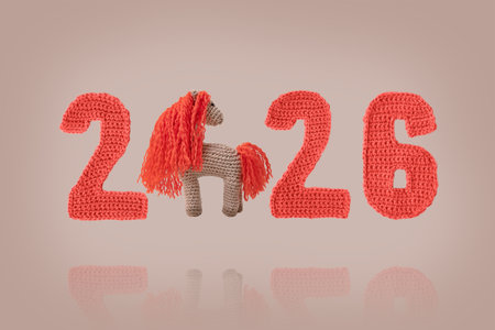 Crocheted toy fiery red horse and red numbers. The symbol of the year 2026 on a beige background. Chinese New Year greeting cardの写真素材
