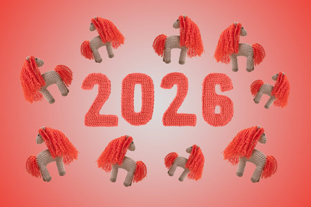 Crocheted toy fiery red horse and red numbers. The symbol of the year 2026 on a beige background.