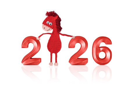 Crocheted toy fiery red horse and red numbers. The symbol of the year 2026 on a white background.