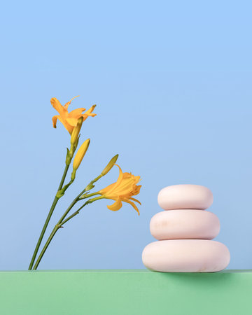Wood slice podium and yellow lily flowers on spring blue background. Concept scene stage showcase for new product, banner, promotion sale, cosmetic, presentation.の写真素材