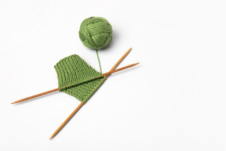 Green knitted wool on gray background with knitting needles for knitting warm clothes and hobbies...