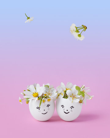 White Easter eggs with funny face and spring flowers on a pink blue gradient background. Happy...