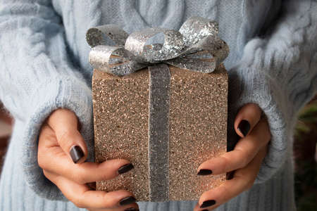 Christmas glowing golden box in woman hands with black manicureの写真素材