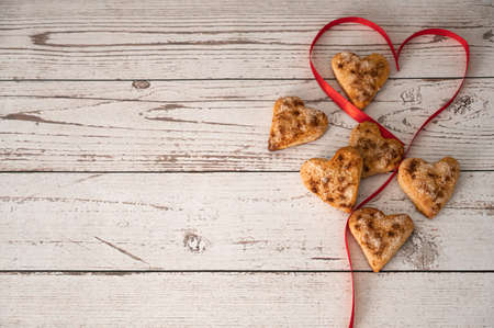 Wooden calendar show of February 14 and heart shaped handmade cookies tied with red satin ribbon on the wooden background. Copy space. Close up. Perfect for designers. St Valentine concept.の写真素材