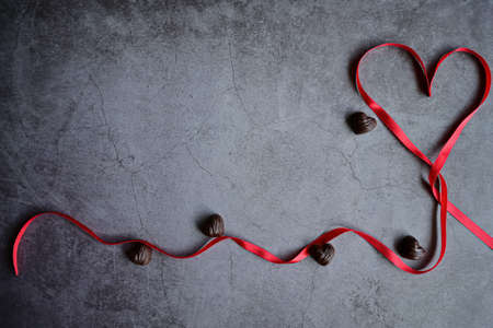 Wooden calendar show of February 14 and box of heart shaped chocolates. Red rose wrapped in ribbon. Lifestyle, copy space. St Valentines day concept.の写真素材