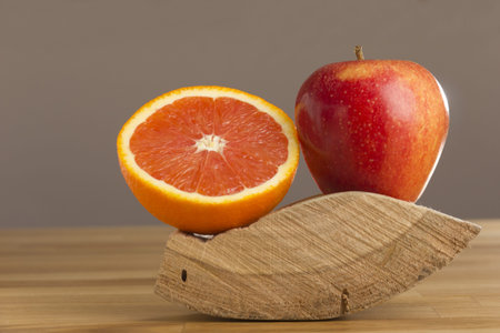 Orange and apple lying on woodの写真素材