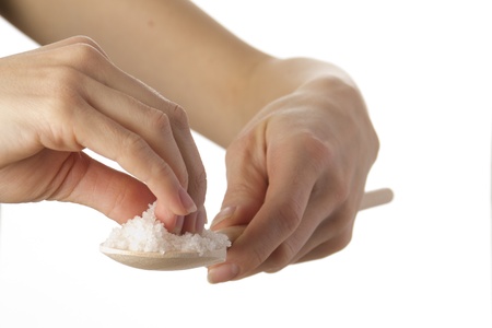 female hands holding salt on wooden spatulaの写真素材
