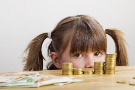 Girl looking at towers of moneyの写真素材