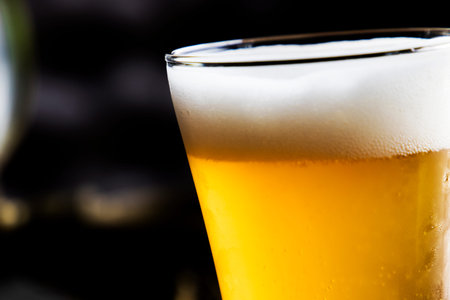 Ice cold beer golden in color with beautiful white froth white frothy beer in a glass