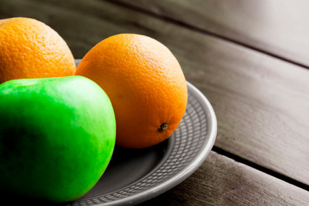 beautiful fruits green apple and orage on a plate set on a woode table.の写真素材
