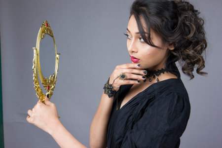 beautiful female model in fashionable black gown in front of a solid backgroundの写真素材