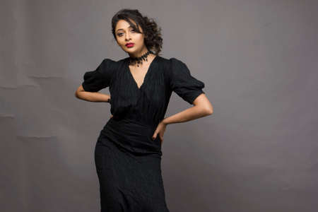 beautiful female model in fashionable black gown in front of a solid backgroundの写真素材