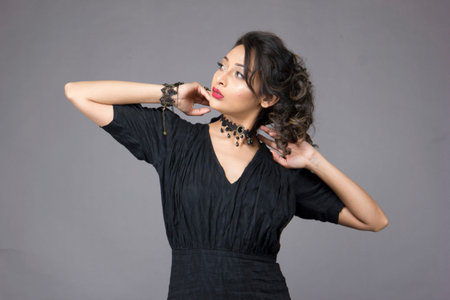 beautiful female model in fashionable black gown in front of a solid backgroundの写真素材