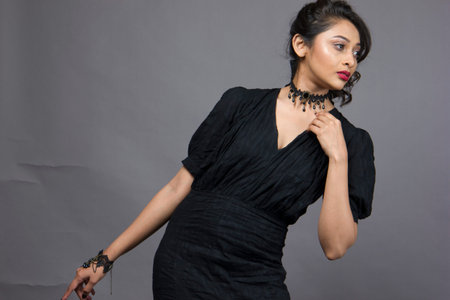 beautiful female model in fashionable black gown in front of a solid backgroundの写真素材