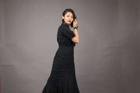 beautiful female model in fashionable black gown in front of a solid backgroundの写真素材