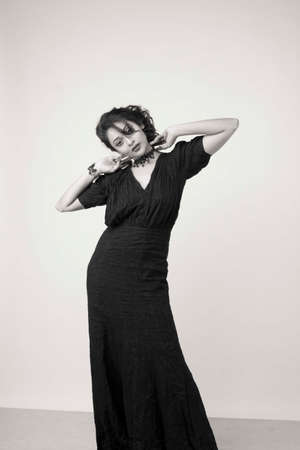 beautiful female model in fashionable black gown in front of a solid backgroundの写真素材