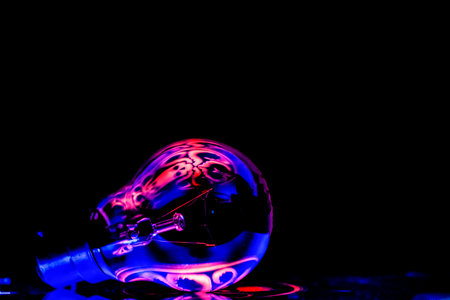 A closeup shot of a glass light bulb with blue and pink reflectionsの写真素材