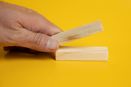 placing a wooden blocks on two blocks arranged neatly on a solid yellow background.の写真素材