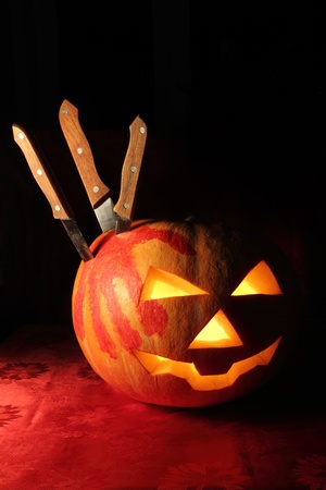 pumpkin for Halloween with a track of blood-stained palm and several knivesの写真素材