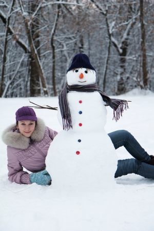 Beautiful brunette near a snowmanの写真素材