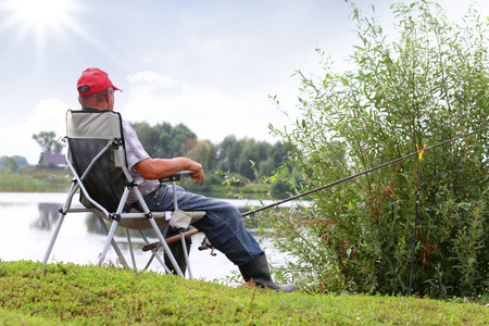 Fisherman fishes in the river. Middle aged man. の写真素材