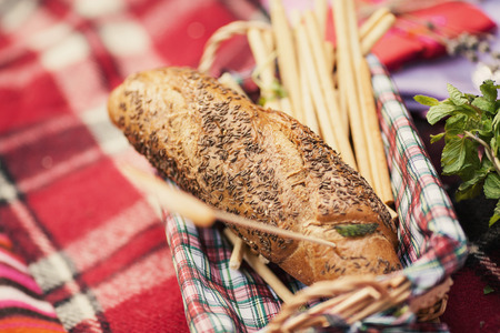 Beautiful bread with caraway seeds close-up lying in a basket on plaidの写真素材