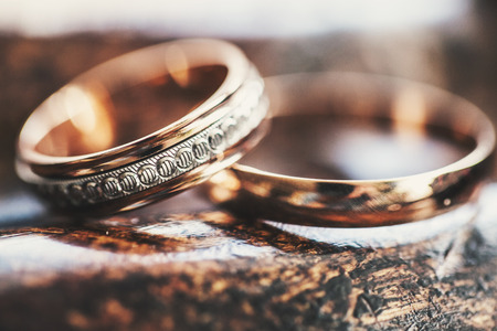 Two gold wedding rings lie on a wooden surfaceの写真素材
