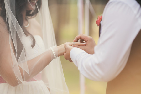 The groom wears his beautiful bride wedding ringの写真素材