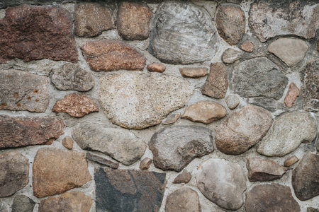Background of a stone wall closeup. Texture of large and small multi-colored stones in concrete. Old rough concrete wall made of many stonesの写真素材