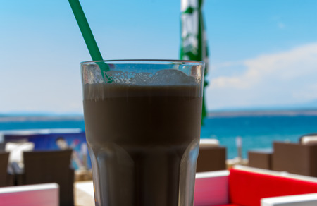 Ice-coffee in the beach bar in a cool shade looking over the oceanの写真素材