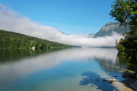 Lake Bohinj and surrounding mountains in fog on a summer morningの写真素材