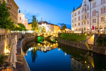 Reflection in Ljubljanica river and surrounded buildings on a summer evening in Ljubljanaの写真素材