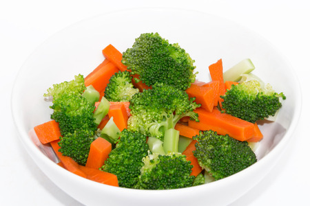 Fresh carrots and broccoli in a white bowl on a white background.の写真素材