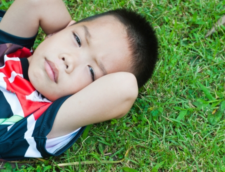close up of little boy lying on a green grassの写真素材