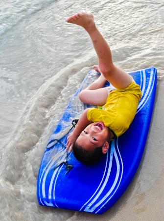 Happy Little boy with surfboard on the beachの写真素材