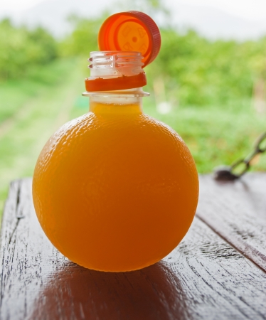 Orange juice in bottle on the wood table with green background の写真素材