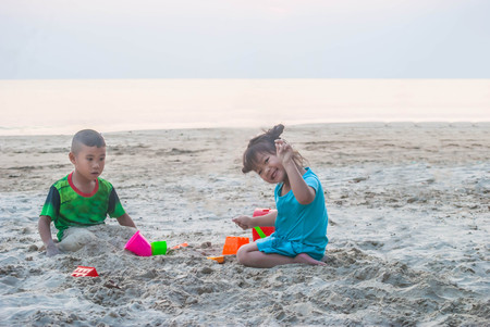 Asian little boy and girl are playing together on the sandy beach.の写真素材