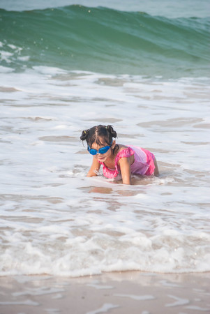 Cute asia girl having fun on the sunny tropical beach with wonderful waves around her.の写真素材