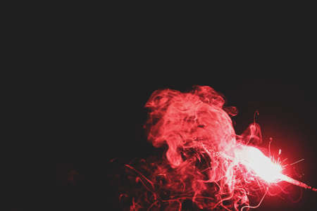 A pink pencil sparkler cracker burning  on Diwali night on black background with fire and smokeの写真素材