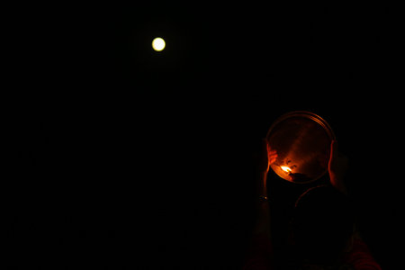 night view of karwa Chauth pooja with a glowing diya against the moon