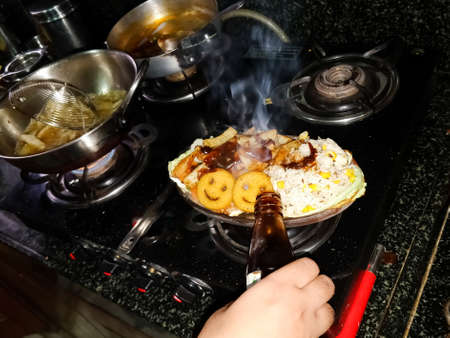 pouring ingredients while cooking food on the stoveの写真素材