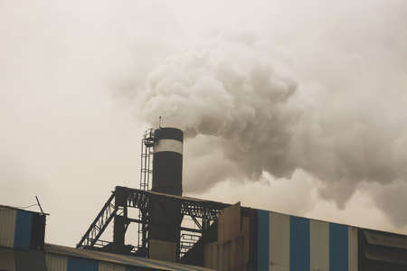 smoke coming out from the chimney of a factory industryの写真素材