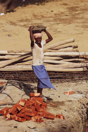 A daily wage worker carrying raw material for construction(bricks, sand)のeditorial素材